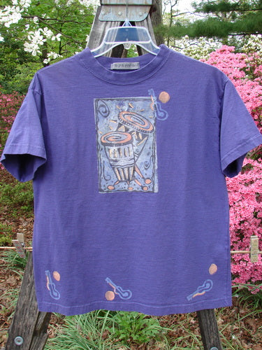 Vintage 1996 Short Sleeved Tee Drum Niagara Size 0 from BlueFishFinder.com: Purple tee with a picture, featuring a thicker ribbed neckline, drop shoulders, and a square boxy shape. Signature Blue Fish patch with a drum theme.