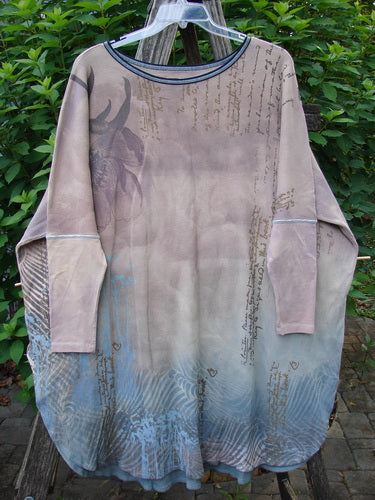 Barclay Thermal Contrast Revival Top Script Pastels OSFA displayed on a rack, showcasing its ribbed sleeves, rounded neckline, and varying A-line shape with side vents and continuous script theme.