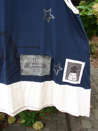 1998 8 Ball Tunic Games Crew Blue Size 1: A sleeveless navy and off-white tunic with abstract emblem and blue fish patches, featuring a scoop neckline and racerback, hung outdoors.