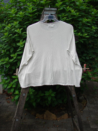 Barclay Cotton Slub Cricket Cap Sleeve Tee Stone Blossom Creme OSFA displayed on a clothes rack, showcasing its unique square boxy shape, seamless shoulder sleeves, and rounded hemline, made from lightweight organic cotton.
