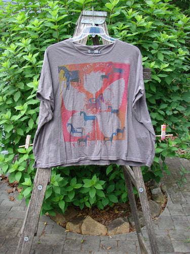 Barclay Cotton Slub Cricket Cap Sleeve Tee Primitive Pony Dark Stone OSFA on a wooden ladder, showcasing its boxy shape, seamless shoulder, and primitive pony theme, highlighting its vintage Blue Fish Clothing style.