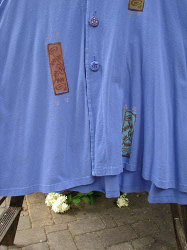 1997 Simple Vest Flower Sprig Skylark Size 2: A blue shirt with a brown and white design, featuring a close-up of white flowers and a grey brick walkway.
