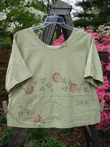 Vintage 1996 Collector's Top from Seedling: A green shirt with floral patterns, wider neckline, A-line flare, and charming pockets adorned with original paper buttons. Reflects Blue Fish's creative freedom in women's fashion.