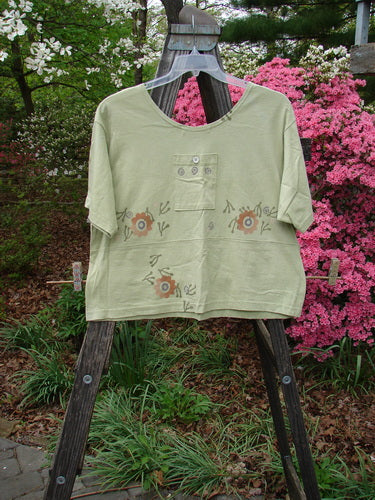 1996 Collector's Top Floral Seedling Size 2: A green shirt with floral patterns, featuring a wider neckline, A-line flare, and charming pockets adorned with original paper buttons. Reflects BlueFishFinder's vintage, creative ethos.