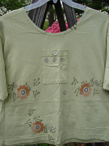 Vintage 1996 Collector's Top from Seedling: A green shirt with floral design, sweet painted neckline, A-line flare, and charming pockets adorned with original paper buttons. Reflecting Blue Fish's creative freedom for women.