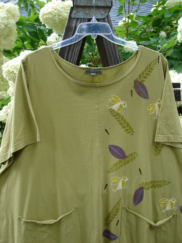 Barclay Double Pocket Twinkle Top Finch Leaf Peapod Size 2: A green shirt with birds on it, featuring a ruffle hem, banded lower sleeves, and double drop pockets. Made from medium weight organic cotton.