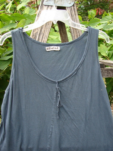 Barclay Batiste Decora Tiny Tank Unpainted Navy Size 2, sleeveless and A-line, hangs on a clear hanger outdoors. Features a vertical tie neckline and diagonal insert, showcasing a lightweight, versatile design.
