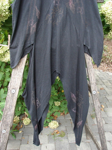 Barclay Calligrapher's Vest Asian Inspiration Black Size 0, featuring a drapey, loose silhouette with a deep V-neckline, dramatic sides, and vintage buttons, displayed outdoors on a wooden frame.