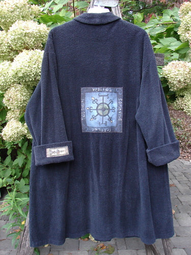 1999 Patched Chenille Angle Pocket Jacket Holiday Black Size 1, featuring a unique hand-painted compass-like patch, displayed outdoors on a wooden rack with cuffed sleeves revealing additional patchwork detailing.