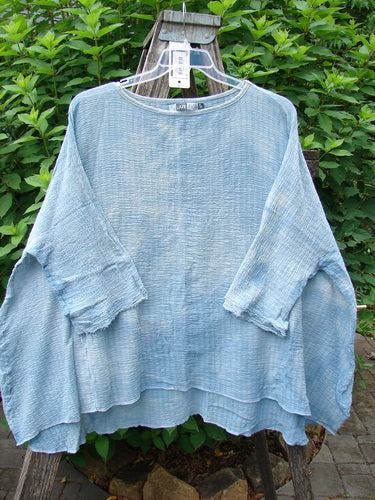 Barclay NWT Crinkle Gauze Top Mottled Smokey Sky Blue OSFA displayed on a white plastic hanger, showcasing its high-low hemline, three-quarter dolman sleeves, and textured crinkle cotton gauze fabric.