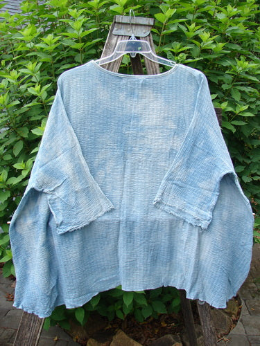 Barclay NWT Crinkle Gauze Top in Mottled Smokey Sky Blue displayed on a swinger, showcasing its wide, boxy silhouette, three-quarter dolman sleeves, and high-low hemline, highlighting its featherweight texture.