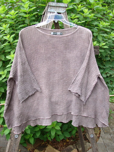 Barclay Crinkle Gauze Top Mottled Steaming Latte OSFA displayed on a clothes rack, showcasing its high-low hemline and three-quarter dolman sleeves with a soft, forgiving texture.