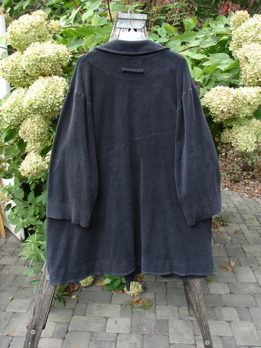 2000 Celtic Moss Highlander Coat Unpainted Black Size 1 draped over a wooden trestle, showcasing its oversized buttons, empire waistline, and dense winter weight fabric, ideal for warmth and style.