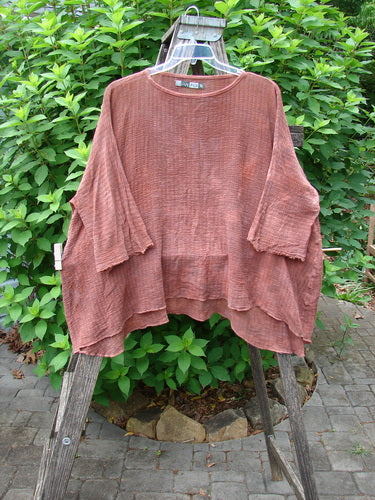 Barclay Crinkle Gauze Top in Mottled Monrovian Brick displayed outdoors on a clothes rack, highlighting its three-quarter dolman sleeves and wide, boxy fit.