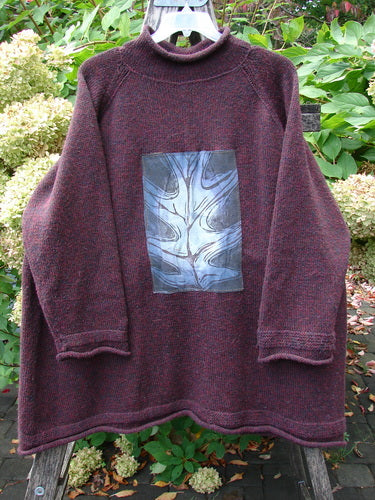 The 1998 Patched Alpaca Roll Neck Raglan Sweater Wineberry Tweed OSFA showcases a burgundy knit with a blue-gray leaf patch, featuring ribbed edges and a distinctive A-line silhouette.