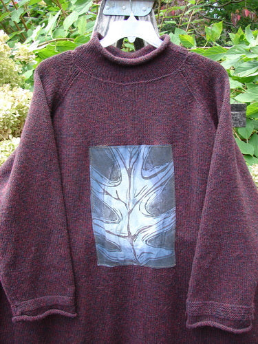 1998 Patched Alpaca Roll Neck Raglan Sweater Wineberry Tweed OSFA features a maroon-heather knit with a mock collar, silvery-blue abstract graphic, and oversized leaf theme patch, hanging outdoors.