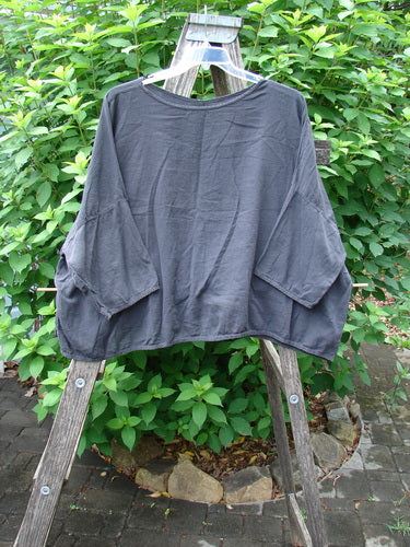 Barclay Twill Atmosphere Overlayer Boxy Top Unpainted Black OSFA displayed on a wooden rack, showcasing its wide, boxy shape, three-quarter dolman sleeves, and rounded neckline, embodying BlueFishFinder's vintage, creative style.