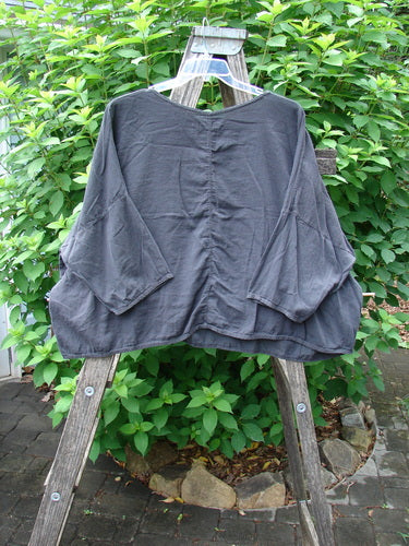 Barclay Twill Atmosphere Overlayer Boxy Top Unpainted Black OSFA displayed on a wooden rack, highlighting its flowy, textured cotton twill fabric, three-quarter dolman sleeves, and sweetly rounded neckline.