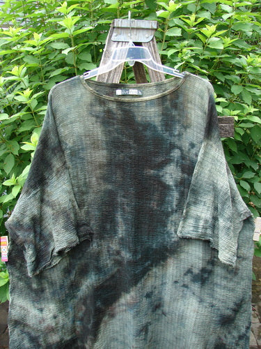 Barclay Crinkle Gauze Ana Tunic Dress Unpainted Mottled Forest OSFA displayed on a wooden ladder outdoors, showcasing its wide three-quarter sleeves, seamless shoulder, and varying hemline.