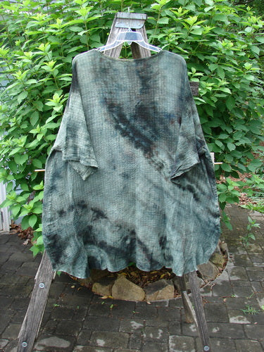 Barclay Crinkle Gauze Ana Tunic Dress in Mottled Forest displayed on a rack, showcasing its seamless shoulders, wide sleeves with frays, and varying hemline, embodying Bluefishfinder.com's vintage style.