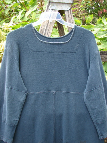 1999 Thermal Home Dress Paisley Peacock Size 0, in a loose, long-sleeved design. Features a squared neckline, rectangle elbow patches, and unique sectional panels. Hangs on a trellis with foliage backdrop.