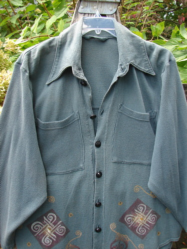 1996 Celtic Filias Jacket Celtic Loch Size 1 with muted green, waffle weave, spread collar, five black buttons, diamond motifs in burgundy, gold accents, and two large chest pockets, hanging outdoors.