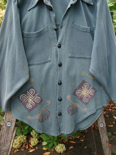 1996 Celtic Filias Jacket Celtic Loch Size 1: A lightweight, muted blue-gray shacket with oversized chest pockets, decorative earth-tone motifs, and shiny diamond-cut buttons, reflecting Blue Fish's unique, creative vintage style.