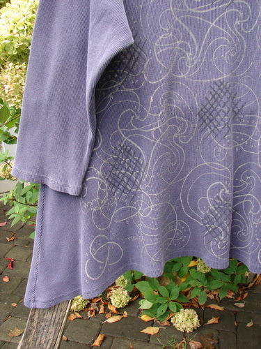 Barclay Thermal A Lined Top Spirograph Plum Size 2 draped on a wooden bench, showcasing its abstract swirl and crosshatch print, rounded neckline, and long sleeves amidst greenery, embodying Bluefishfinder's creative vintage style.
