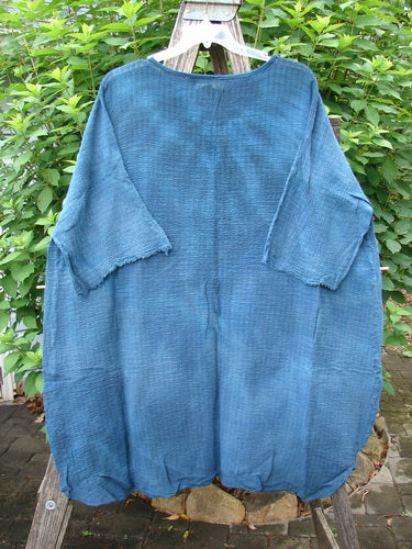 Barclay NWT Crinkle Gauze Ana Tunic Dress in Mottled Teal on a rack, showcasing its wide three-quarter sleeves, seamless shoulder, and varying hemline, reflecting BlueFishFinder's vintage-inspired style.