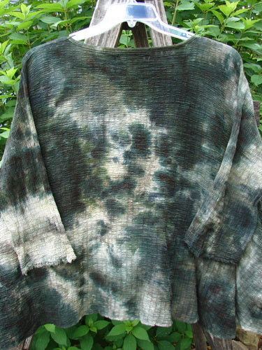 Barclay Crinkle Gauze Crop Top in Mottled Forest Black Sky, displayed on a wooden pole. Features include a high-low hemline, three-quarter dolman sleeves, and a rolled neckline, highlighting its unique texture.
