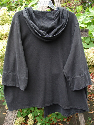 Barclay Fleece Single Button Hooded Jacket Grid Black Size 2 hangs outdoors, showcasing its wide sleeves, cozy hood, single button closure, and unique grid design against a lush plant backdrop.