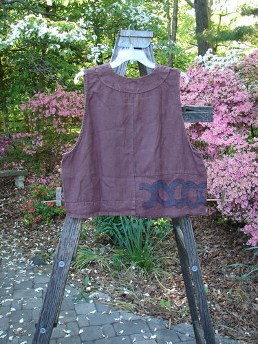 2000 Poet's Vest Celtic Loam Size 1 displayed on a wooden stand. The vest features metal buttons, an offset front pocket, double-paneled hemline, unusual front seams, and feathered accents.
