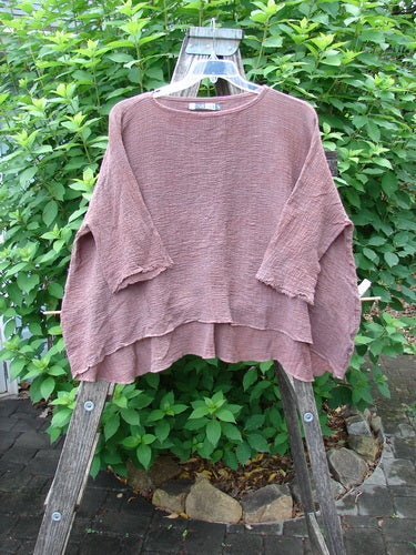 Barclay Crinkle Gauze Crop Top Mottled Monrovian Clay OSFA displayed on a wooden rack, highlighting its boxy shape, three-quarter dolman sleeves, and unique high-low hemline, embodying Bluefishfinder.com's creative vintage style.