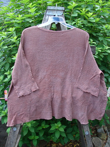 Barclay Crinkle Gauze Crop Top in Mottled Monrovian Clay displayed on a clothes rack, showcasing its wide, boxy shape, dolman sleeves, and high-low hemline, reflective of BlueFishFinder's vintage style.