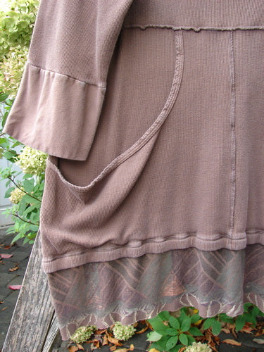 Barclay Thermal Flutter Neck Kangaroo Pocket Top Leaf Mud Size 0 draped outdoors, showcasing its long sleeves, loose pocket, visible seams, patterned chiffon ruffle hem, and deeper V-neck with sailor-like collar.