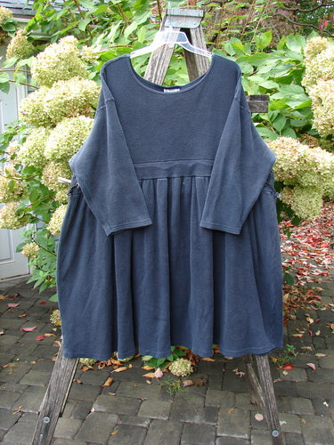 1992 Thermal Circus Dress Unpainted Black Size 2 displayed on a wooden ladder, showcasing its loose fit, wide rounded neckline, gathered empire waist, and slightly shorter than full-length sleeves.