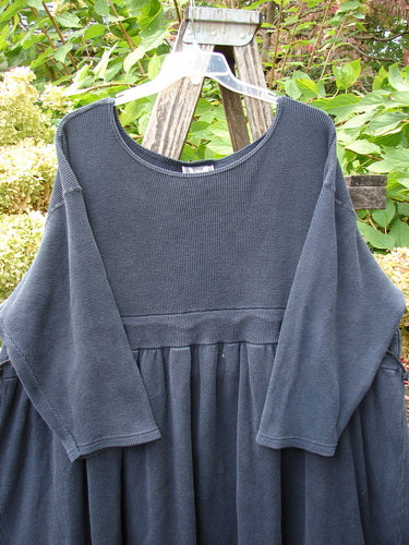 1992 Thermal Circus Dress Unpainted Black Size 2, displayed on a wooden A-frame, features a loose, empire-waist design with a wide neckline, gathered folds, and distinctive metal grommets.