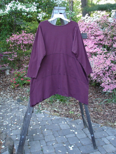 Barclay Cotton Lycra Shape Dress Unpainted Burgundy Size 1 displayed on a rack, showcasing its soft neckline, long sleeves, deep pockets, and unique hemline.