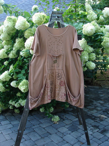 A brown tunic dress with artichoke garden theme paint. Generous measurements, oversized front pockets, and a rounded neckline. Size 2.