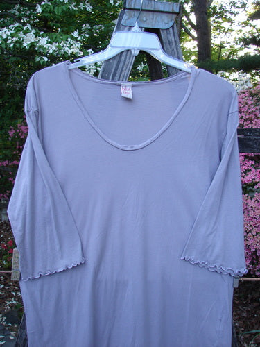 Barclay Batiste Round Bottom Shirt in Lavender displayed on a hanger, featuring a deep neckline, three-quarter sleeves, and a rounded hem with side vents.