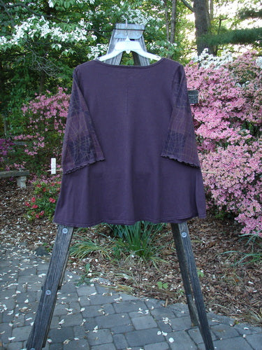 Barclay Three Quarter Grid Sleeved A Line Top Plum Size 1 showcased on a hanger against a backdrop of lush greenery, embodying BlueFishFinder's vintage charm and creative freedom in women's fashion.