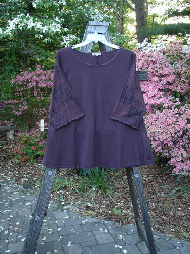 Barclay Three Quarter Grid Sleeved A Line Top Plum Size 1 displayed on a clothes rack outdoors. Features a rounded neckline, fluttery edged sleeves, and a linear grid pattern. Vintage Blue Fish Clothing by Jennifer Barclay.