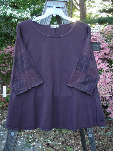 Barclay Three Quarter Grid Sleeved A Line Top Plum Size 1, showcasing a purple shirt with a unique grid pattern on fluttery edged sleeves. Vintage Blue Fish Clothing's creative freedom for women's individuality.