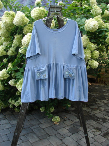 Barclay Collector's Tunic Dress Starburst Faded Sky Size 2: A blue shirt with exterior painted pockets on a rack.