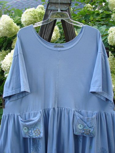 Barclay Collector's Tunic Dress Starburst Faded Sky Size 2: A blue shirt with pockets on a swinger, featuring a drop waistline and a flouncy lower skirt adorned with dandelion flowers.