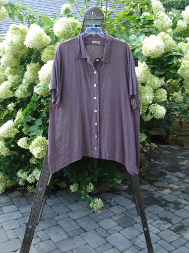 A plum checker Barclay Pucker Cotton Short Sleeved Gingham Shirt on a swinger, featuring a tidy collar, an A-line shape, and generous short sleeves.