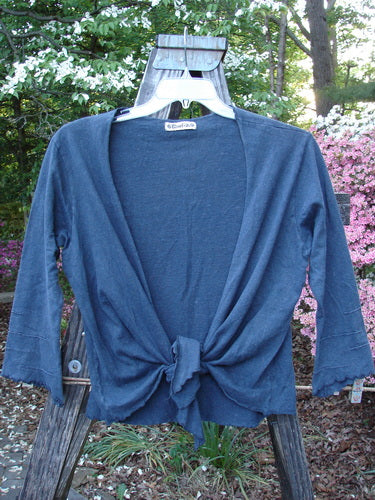 Barclay Hemp Cotton Long Pinch Sleeved Shrug Unpainted Navy Size 1 displayed on a wooden swing outdoors, showcasing its deep V neckline, front tie wrap, and unique pinched sleeve accents.