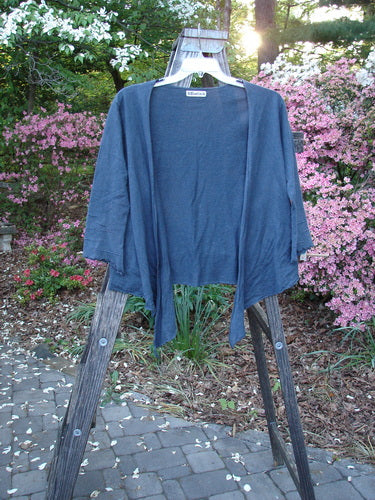 Barclay Hemp Cotton Long Pinch Sleeved Shrug Unpainted Navy Size 1 displayed draped over a rustic wooden ladder, showcasing its deep V neckline, front tie wrap, and distinctive pinched sleeve accents.