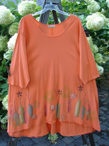 A Barclay Hi Low Tunic Top in Tangerine, featuring a soft neckline, varying hemline, and modern vase theme paint. Size 2.