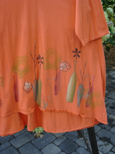 A close-up of the Barclay Hi Low Tunic Top in Tangerine, made from Organic Cotton. Features include a rounded neckline, varying hemline, and longer three-quarter sleeves. Size 2.